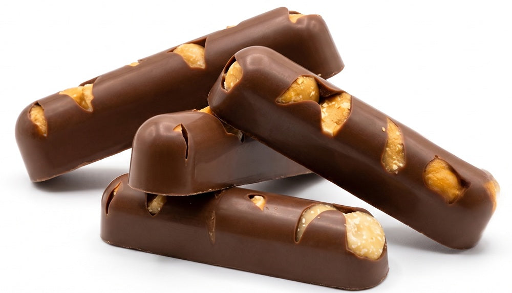 Four milk chocolate fingers stacked on a white background, each topped with pieces of dried mango.